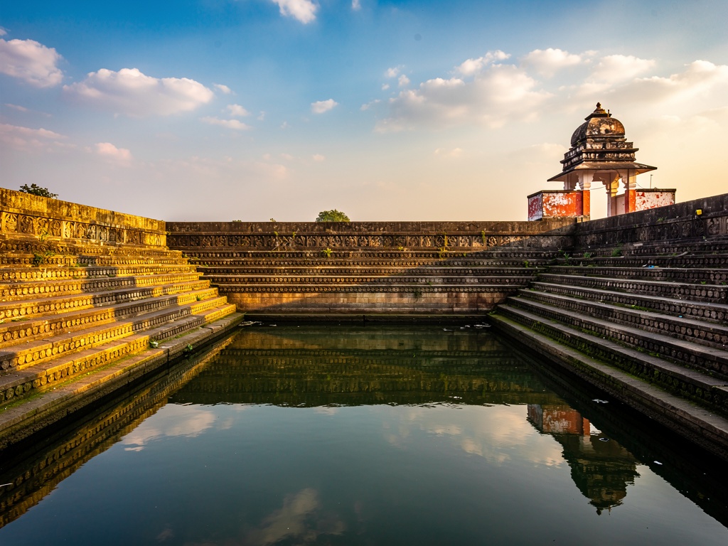 An ancient carved stone tank in Kolhapur reflecting the sky